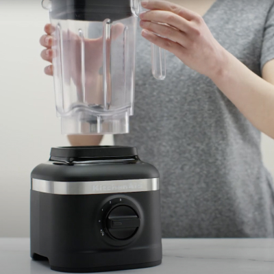 Person removing blender jar from black base of KitchenAid® blender